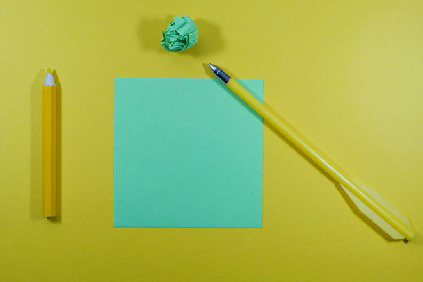A top view of a yellow pen, pencil, empty and crumpled papers isolated on a yellow background - Фото, зображення