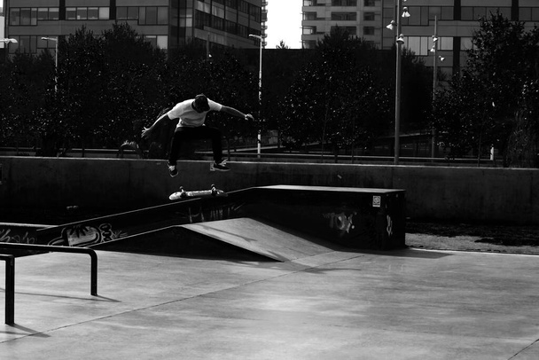 A selective focus shot of silhouette of an unrecognizable skateboarder showing different tricks at the skate park by Mediterranean sea of Barcelona - Фото, изображение
