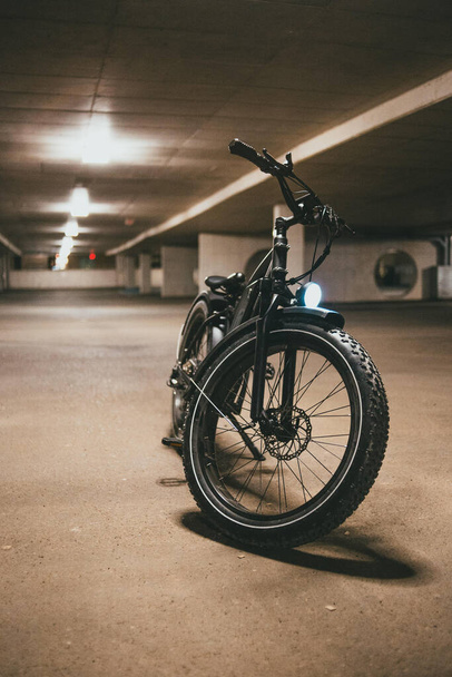 A cool black trial motorbike in a dark underground parking lot - Foto, imagen