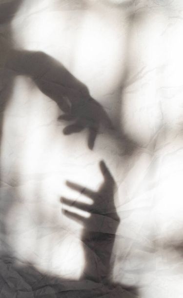 Sombras cinzentas de mãos que se alcançam na parede. Efeito abstrato turvo. Foco nas sombras. - Foto, Imagem