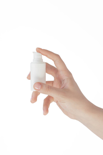 plastic white bottle in a female hand on a white background, skin care, cosmetic product, acne treatment, hand sanitizer, coronavirus - Fotografie, Obrázek