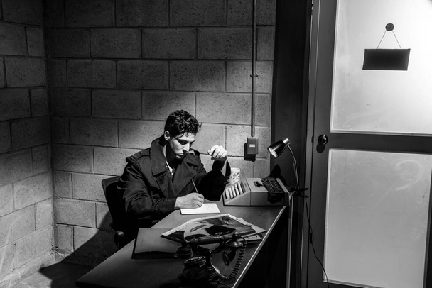 Dark and dramatic scene in a detective's office. heavy smoke. Detective working in a desk. Bkack and white. - Photo, Image