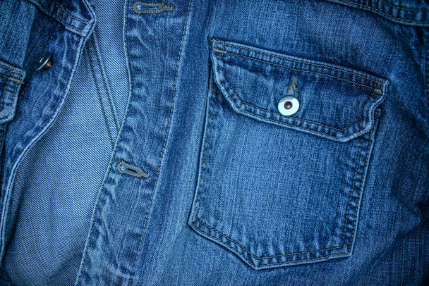 Photo of the texture of a denim jacket with a blue pocket and metal rivets - Photo, Image