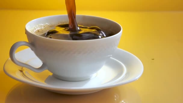 Un trozo de azúcar cae lentamente en una taza de café con salpicaduras. - Metraje, vídeo