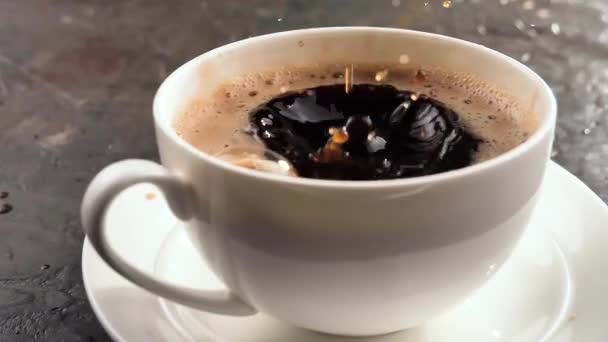 Une goutte tombe lentement dans le café dans une tasse - Séquence, vidéo