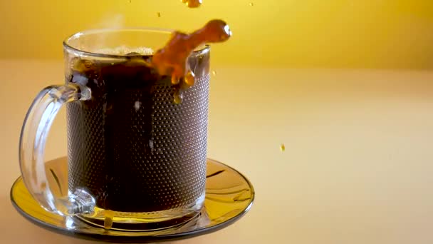 Kawałek cukru powoli wpada do filiżanki kawy z rozpryskami.. - Materiał filmowy, wideo