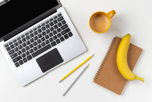 Flat lay top view modern laptop, food and stationery on white table - Foto, Imagem