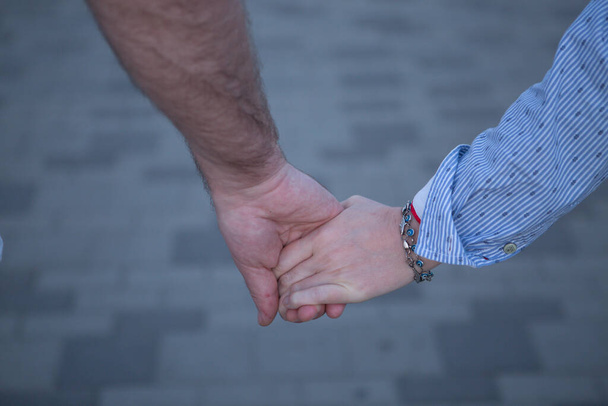 Nahaufnahme eines liebenden Paares, das sich beim Gehen an den Händen hält. Konzept Liebe und Emotionen. - Foto, Bild