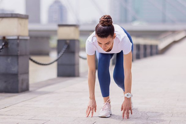 Young brunette Woman running on asphalt road in summer park. Active sporty caucasian female has morning workout. Athletic person in sportswear exercises outdoor. Dressed leggings and sportive top - Photo, Image
