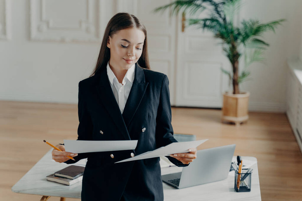 Successful business lady looking documents during working day in office - Photo, Image
