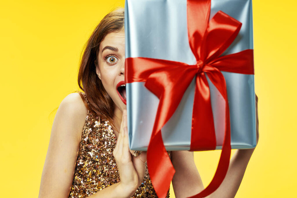 Frau hält ein Geschenk Urlaub Weihnachtsdekoration gelb Hintergrund - Foto, Bild