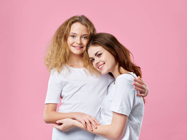 mom and daughter hug family joy pink background - Foto, Bild