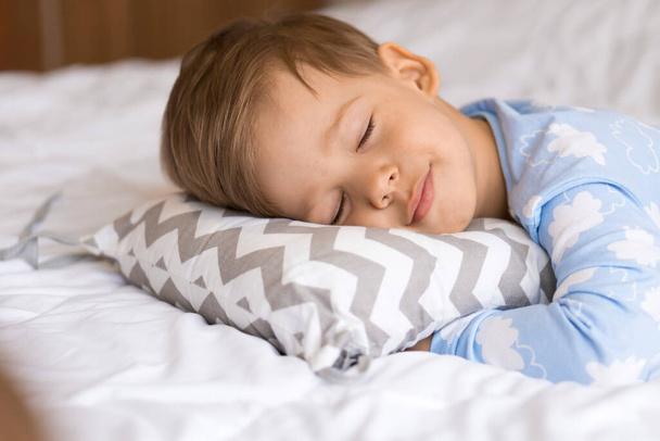 home, comfort, childhood, care, love, sweet dream- little pretty smiling happy authentic toddler sibling kid child boy in pajamas lie rest sleep on bed pillows with closed eyes soft cozy sleepy mood - Foto, Bild