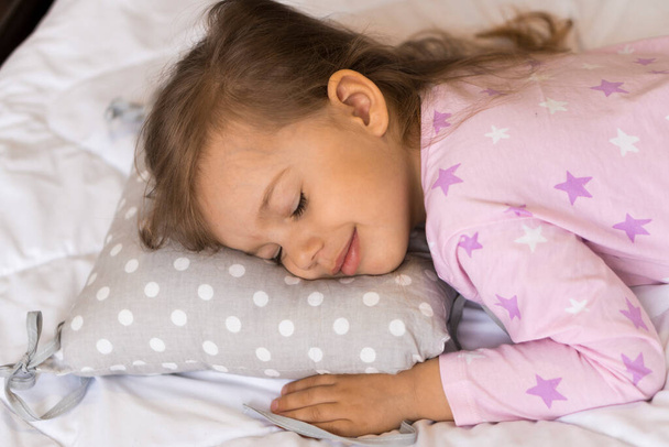 home, comfort, childhood, care, love, sweet dream- little pretty smiling happy authentic toddler sibling kid child girl in pajamas lie rest sleep on bed pillows with closed eyes soft cozy sleepy mood - Φωτογραφία, εικόνα