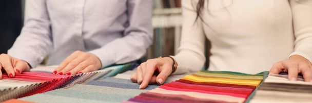 Designer and client choosing fabric in catalog closeup - 写真・画像