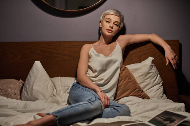Tired female sit on bed alone having unhappy facial expression - Valokuva, kuva