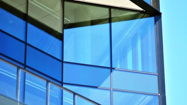 Facciata in vetro degli edifici con un cielo blu. Moderno edificio nel centro della città d'affari. Sfondo di moderni edifici in vetro.  - Foto, immagini