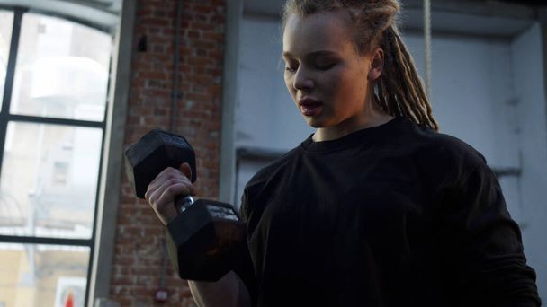 A strong athletic woman is making an exercise with a dumbbell - Photo, Image