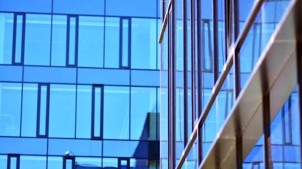 Glazen gevel van de gebouwen met een blauwe lucht. Modern gebouw in het zakencentrum. Achtergrond van moderne glazen gebouwen.  - Foto, afbeelding