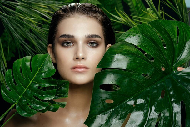 woman with green leaves Exotic bare shoulders clear skin against - Foto, afbeelding