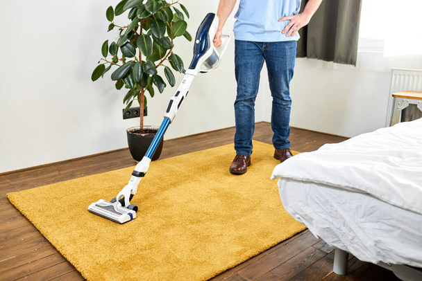 cropped male cleaning floor with vacuum cleaner in modern white living room - Fotó, kép