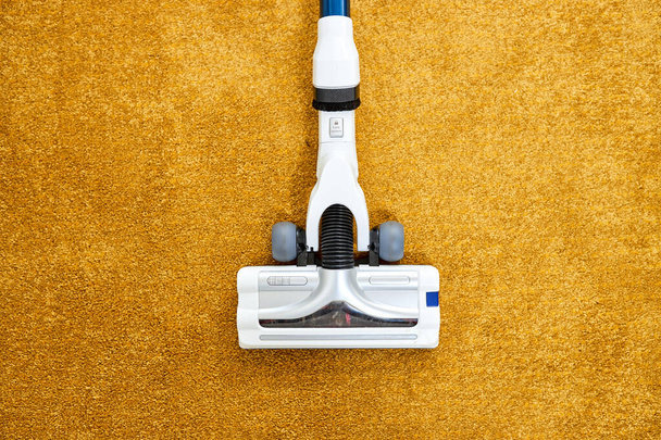Close-up photo of vacuum cleaner applied on yellow carpet at home removing dust - Fotografie, Obrázek