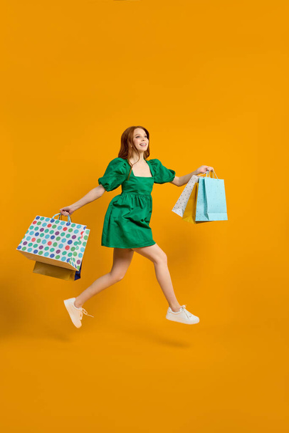 Enjoying of purchasing. Happy excited stylish lady holding many shopping packs, jumping - Foto, afbeelding