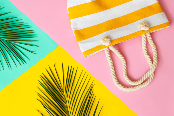 Trendy summer flat lay. Palm leaves and beach bag on a yellow, pink and turquoise background. Vacation concept. Top view. - Foto, afbeelding