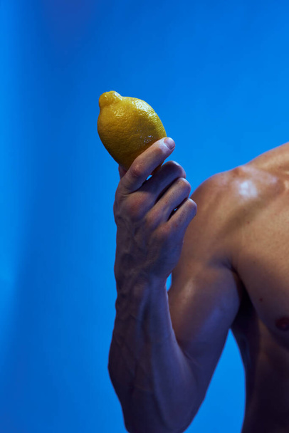 urheilu mies sitruuna kädessä kehonrakentaja sininen tausta - Valokuva, kuva
