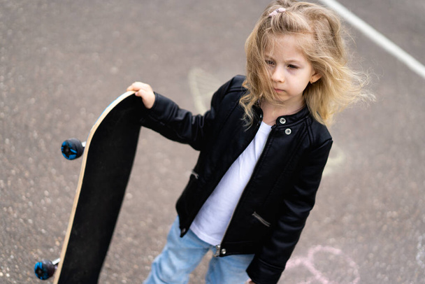 Маленька блондинка на скейті в місті
.  - Фото, зображення