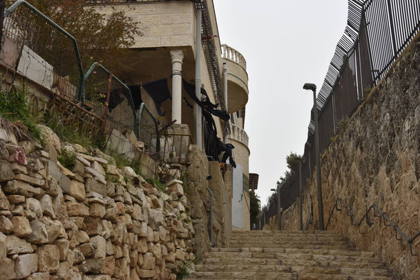 edifício de pedra residencial em Jerusalém, Israel com roupas pretas em um varal. Foto de alta qualidade - Foto, Imagem