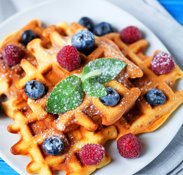 Homemade Belgian waffles served with fresh berries on white plate over wooden background, close up. Flat lay, Top view. - Photo, image