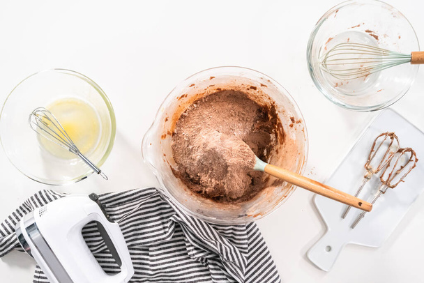 Flat lay. Mixing ingredients in a glass mixing bowl to bake chocolate cookies. - Photo, Image