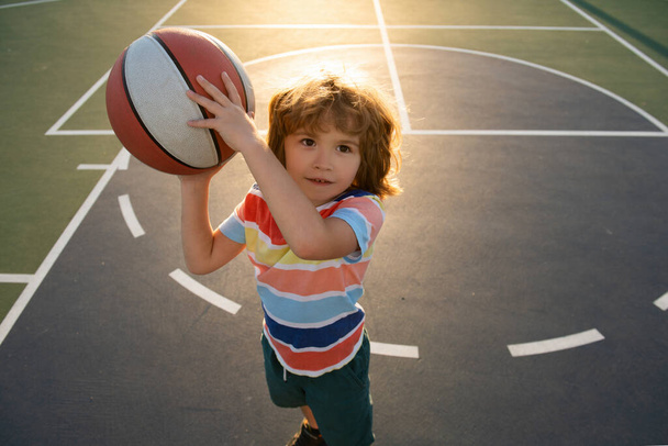 Kid playing basketball. Child boy preparing for basket ball shooting. Best sport for kids. Active kids lifestyle. - Foto, afbeelding