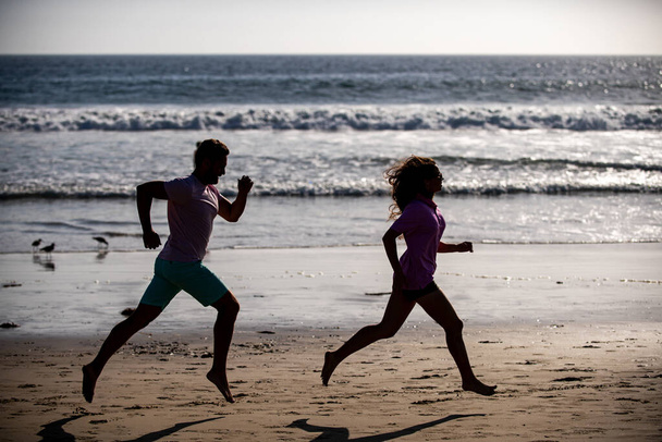 Couple running on beach. Sport and healthy lifestyle, silhouette friends jogging at sunset on the beach. - Foto, Bild