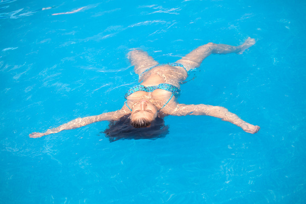 Young woman relaxing in swimming pool - Foto, imagen