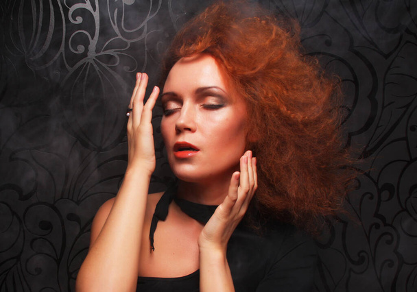 Portrait of beautiful fashion woman model with elegance make-up and curly red hair over dark background. - Фото, изображение