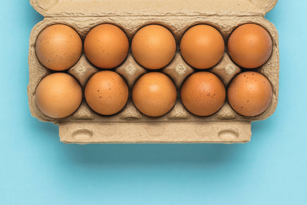 Una caja abierta de huevos sobre un fondo azul claro. Un producto natural. - Foto, Imagen