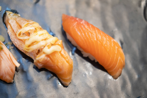 Sushi au saumon brûlé avec sauce mayoungnes et sushi au saumon frais servi dans une assiette au restaurant japonais. - Photo, image