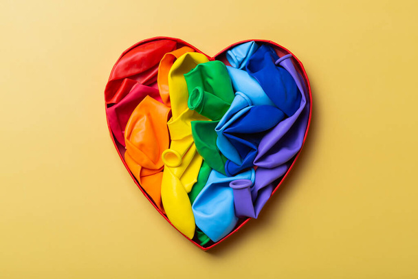 Heart shaped rainbow lgbtq flag against yellow background, pride month - Photo, Image