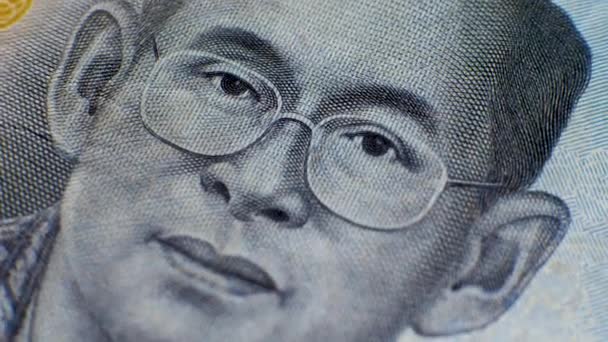 Лицо девятого короля Таиланда Рамы IX в очках на банкноте бат THB - Кадры, видео