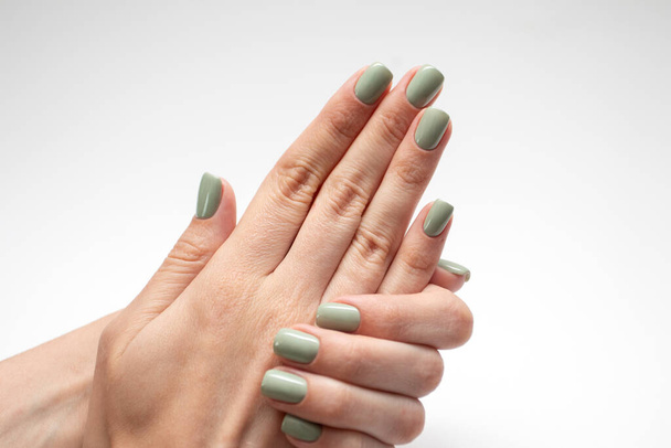 Красивые женские руки с зеленым ногтем. Свежий маникюр на белом фоне. - Фото, изображение