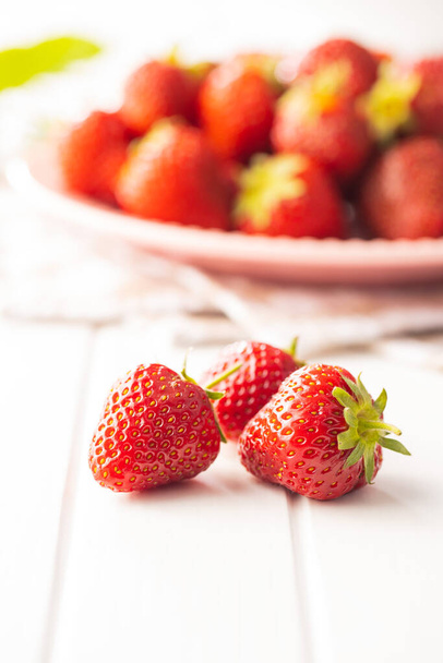 Whole ripe red strawberries on white table. - Foto, afbeelding