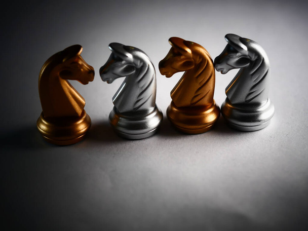 A closeup shot of metallic gold and silver chess horse pieces - Zdjęcie, obraz