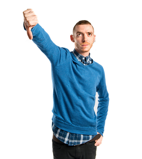 Young man with thumbs down over white background  - Fotografie, Obrázek
