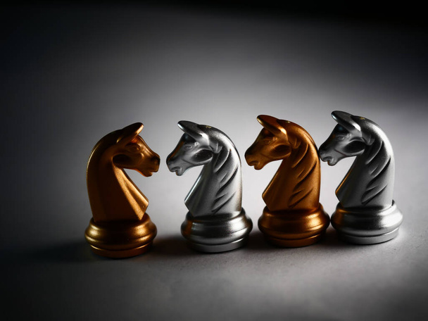 A closeup shot of metallic gold and silver chess horse pieces - Foto, Bild