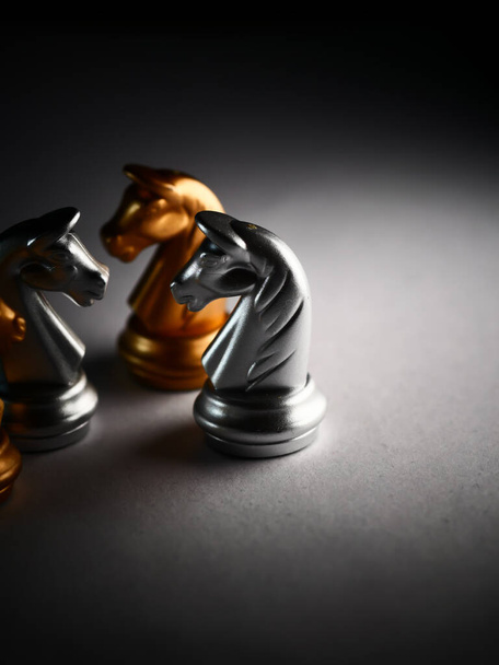 A vertical closeup shot of metallic silver and gold horse chess pieces - Foto, afbeelding