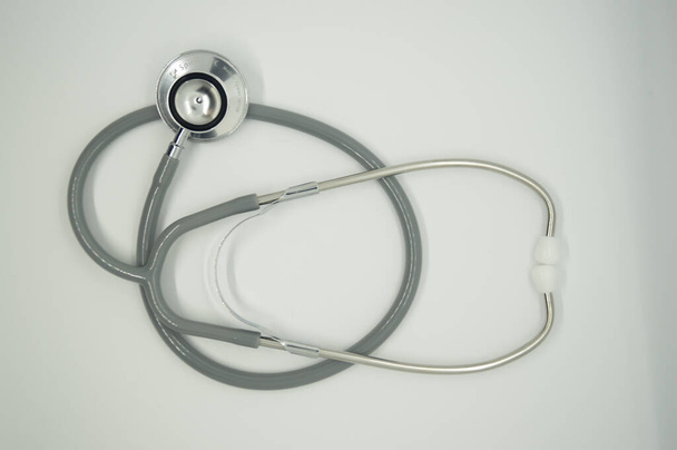 Bovenaanzicht van een grijze stethoscoop op een wit oppervlak - Foto, afbeelding