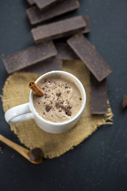A vertical shot of delicious coffee in a mug with cinnamon and dark chocolate bars - Foto, Imagen