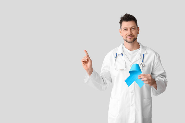 Onkolog s modrou stuhou ukazující něco na světlém pozadí. Koncept povědomí o rakovině prostaty - Fotografie, Obrázek
